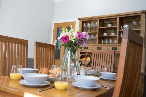 a wooden table with a vase of flowers and bowls at Cherry Tree Villa in Harrogate