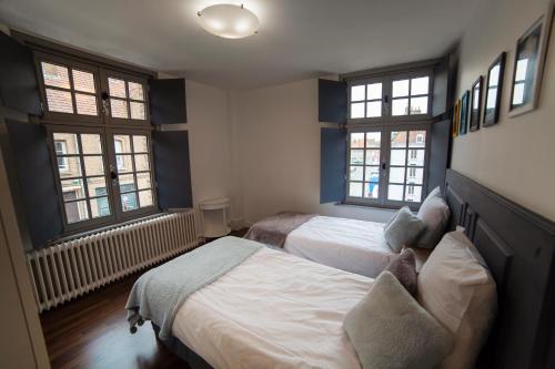 a bedroom with two beds and two windows at Bienvenue Chez Nous in Bergues