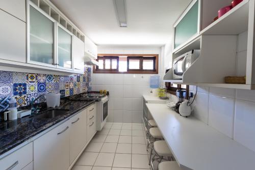 a large kitchen with white cabinets and counters at Batur 102 - Bali Bahia in Praia do Forte