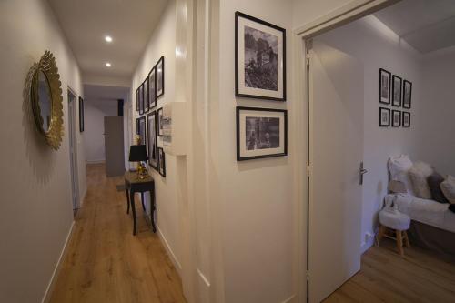 a hallway with a white wall with pictures on it at Bienvenue Chez Nous in Bergues