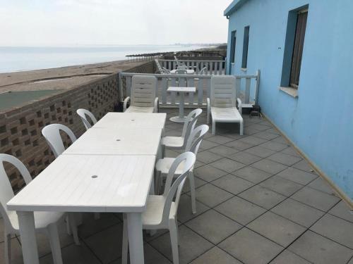 d'une terrasse avec des tables et des chaises blanches et la plage. dans l'établissement VIRGOLA ZERO HOLIDAY BEACH, à Porto Potenza Picena