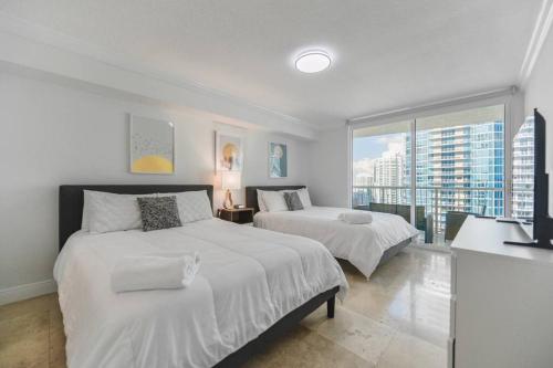 two beds in a bedroom with a view of a city at Centric Modern 40thFloor Brickell Condo FREE parking by Palermo Home Miami in Miami