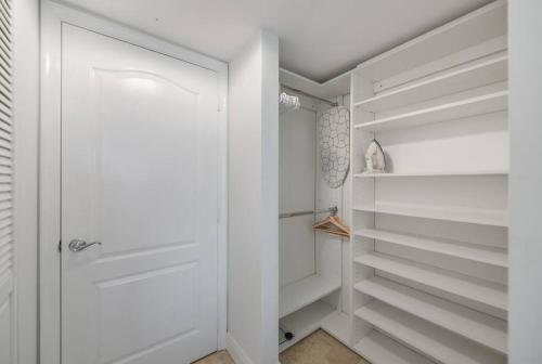 a white walk in closet with white shelves at Centric 40thFloor Brickell Condo FREE parking by Palermo Home Miami in Miami