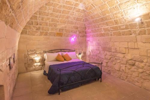 a bedroom with a bed in a stone wall at Suite dei Longobardi in Lecce