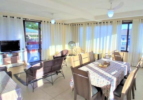 a dining room with a table and chairs and a television at Apartamento Vista para o Mar in Maresias