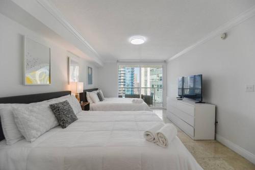 a bedroom with two beds and a flat screen tv at Centric 40thFloor Brickell Condo FREE parking by Palermo Home Miami in Miami