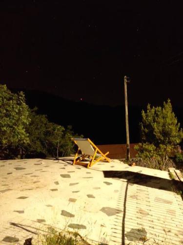 a chair sitting on the beach at night at Charlami's Mansion -Παραδοσιακό Πέτρινο Σπίτι με Τζάκι και Πανοραμική Θέα in Polýdroson