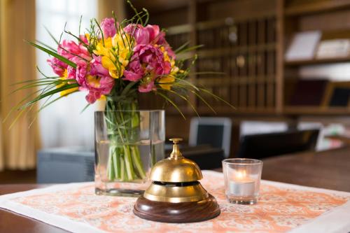 un jarrón de flores sentado en una mesa con una vela en Hotel Gumberger GmbH Garni, en Neufahrn bei Freising