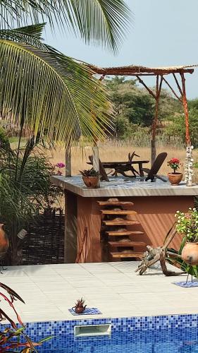 a patio with a table and a pool with plants at AKINE TI KASSO piscine in Diembéreng