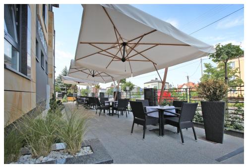 a patio with tables and chairs under an umbrella at Villa Park in Siedlce
