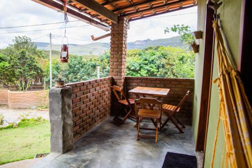 a patio with a table and chairs and a brick wall at Vila Clara do Capão in Vale do Capao