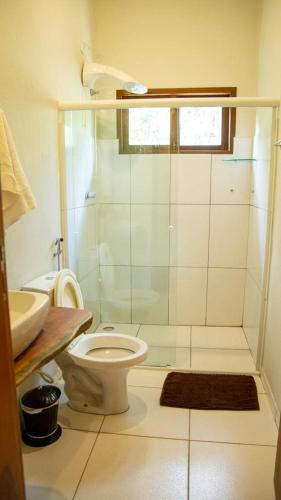 a bathroom with a shower and a toilet and a sink at Vila Clara do Capão in Vale do Capao