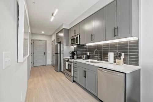 a kitchen with stainless steel appliances and gray cabinets at WhyHotel by Placemakr, Columbia in Columbia