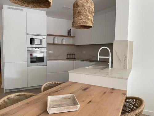 a kitchen with white cabinets and a wooden table at Cap Sa Sal suites -Apartament Begur - Costa Brava in Begur