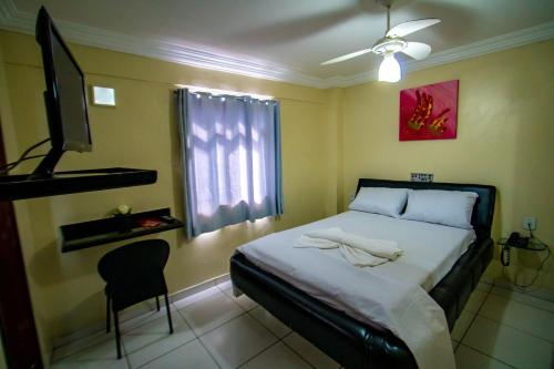 ein Schlafzimmer mit einem Bett, einem TV und einem Stuhl in der Unterkunft Hotel Piramide - Iguatemi in Salvador