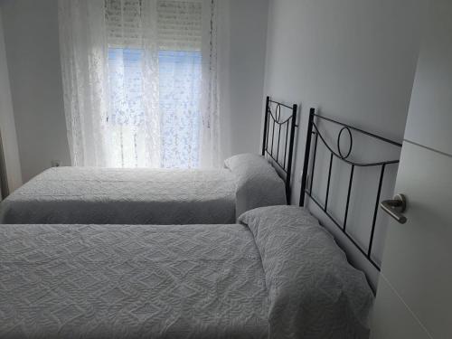 two beds in a bedroom with a window at Nuevo Jerez in Jerez de la Frontera