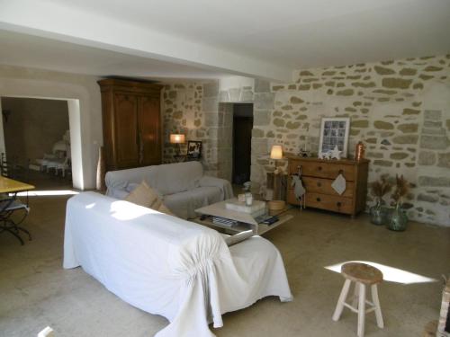 a living room with a white couch and a stone wall at Le petit mas en provence avec piscine in Barbentane