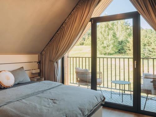 a bedroom with a bed and a balcony with a patio at Między Brzozami in Szczytna