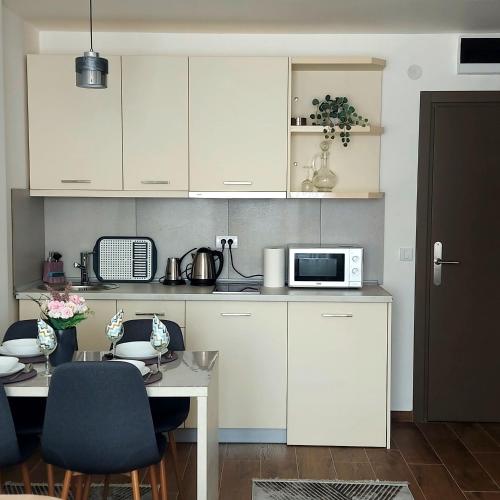 a kitchen with white cabinets and a table with a microwave at Apartman Mery in Kraljevi Čardaci in Kopaonik
