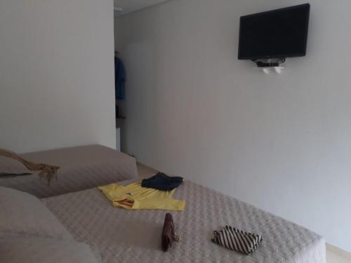 a bedroom with two beds and a flat screen tv at Pousada Aconchego dos Gerânios in Paraty
