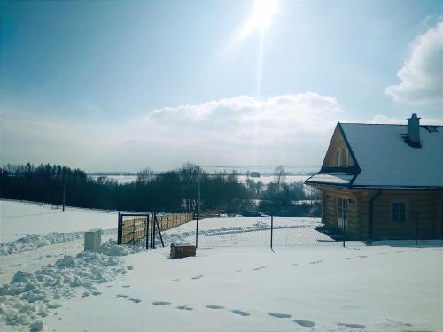 dom w śniegu obok płotu w obiekcie Dom z bala w mieście Lipowa