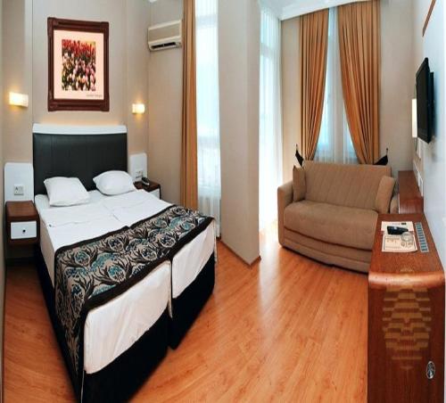 um quarto de hotel com uma cama e um sofá em Azak Hotel em Alanya