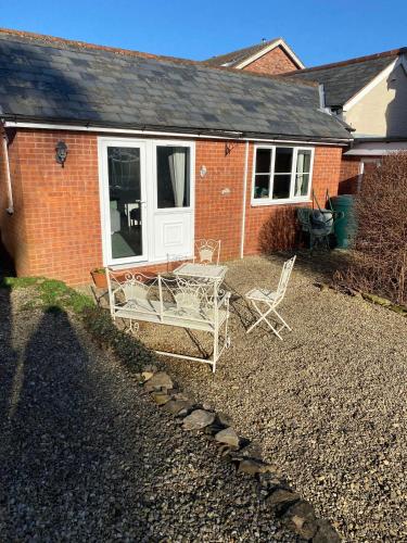 a house with two chairs and a table in the yard at The Coach House at Copper Hall in Leominster