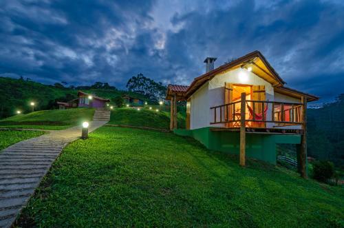 a small house on a grassy hill at night at Pousada Lua de Minas in Visconde De Maua