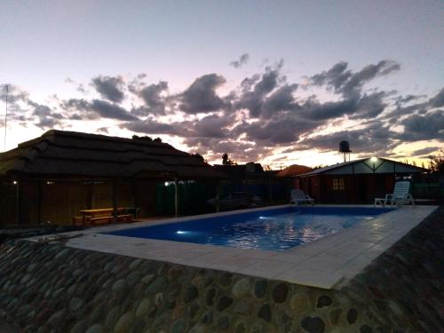 una piscina con puesta de sol en el fondo en Cabaña Bertani en San Rafael