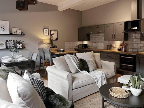 a living room with white couches and a kitchen at Modern Ground Floor Apartment in Todmorden