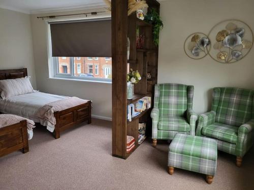 a bedroom with a bed and two green chairs at The Barbers in Beverley