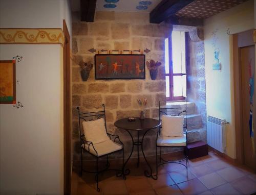 un tavolino e sedie in una stanza con un muro in pietra di Casa Rural Medieval Torre Fuerte S.XIII a Baños de Rioja
