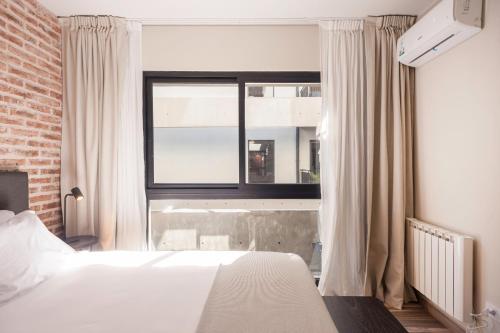 1 dormitorio con cama blanca y ventana en Enjoy Stylish Spacious Apt - La Galerie San Telmo 232 en Buenos Aires