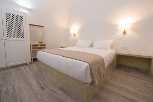 a bedroom with a large bed with white sheets and wood floors at Vivid Caves 2 Bedroom Cavehouse in Foinikiá