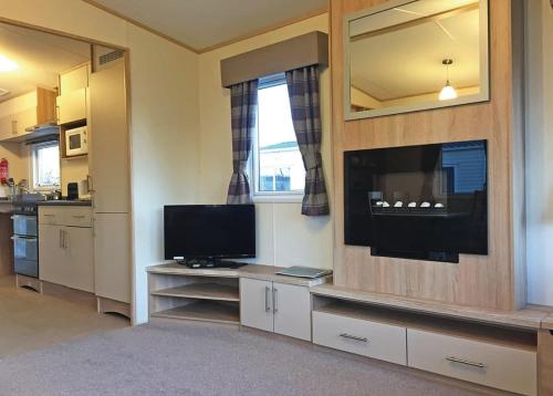 a living room with a television and a kitchen at Tollerton Holiday Park in Huby