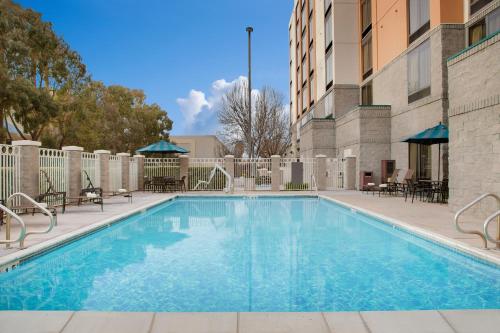 a swimming pool with tables and chairs next to a building at Hyatt Place Fremont/Silicon Valley in Warm Springs District