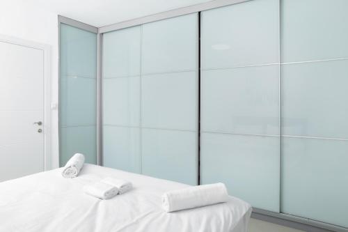 two towels on a bed in a room with glass walls at By Eezy- דירה משפחתית מפנקת 3 חדרי שינה - Hanechoshet in Eilat