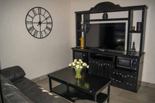 a living room with a couch and a table and a clock at Playas Hotel Suites in Puerto Peñasco