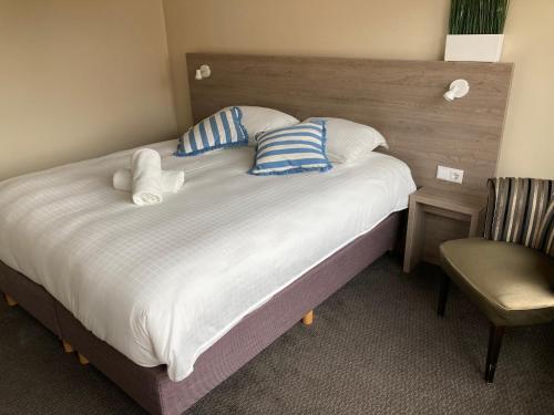 a bedroom with a large bed with pillows and a chair at Fisherman's House by Hofstad Hotels in Scheveningen