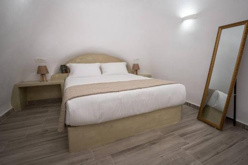 a bedroom with a large bed and a mirror at Vivid Caves 1 bedroom Cavehouse in Foinikiá