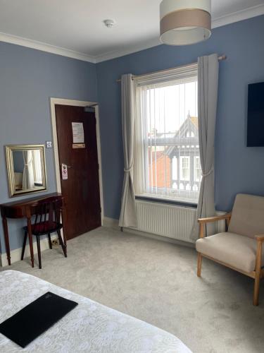 Doriam Guest House في بريدلينغتون: غرفة نوم بسرير ونافذة وكرسي
