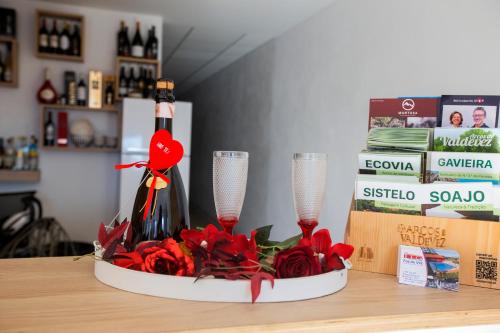 a table with two wine glasses and red flowers at FOZDOVEZ in Souto