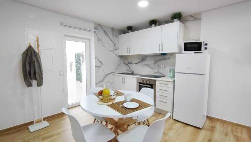 a white kitchen with a table and white appliances at Casa de Praia Daniel in Lavra