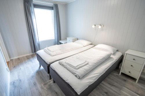 a bedroom with two beds with white sheets and a window at Skaimsberg Holiday Apartments in Aurland
