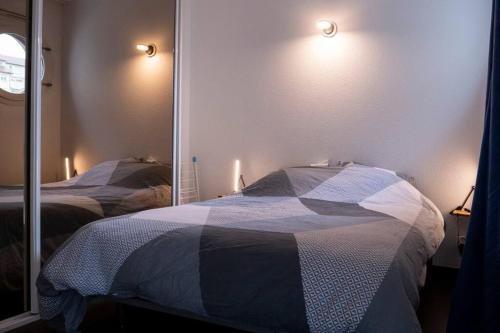 a bedroom with two beds and a mirror at L'île d'Olive, appartement entier 2 à 4 personnes terrasse 25 m2 Besançon, proche CV, Micropolis et CHU in Besançon