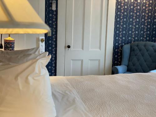 a bedroom with a bed and a blue chair at Central House Inn in Bar Harbor