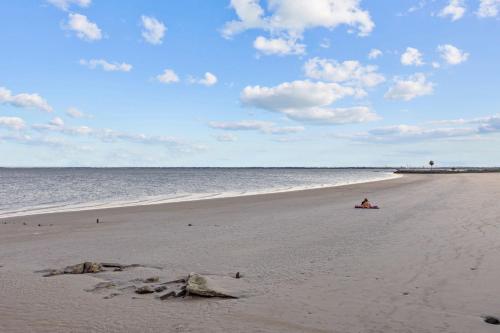 a person sitting on a beach near the water at Seabrook 3BR Near Kemah Boardwalk, El Jardin Beach in Seabrook