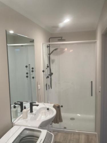 a white bathroom with a sink and a shower at Cambridge Te Awa Rivertrail BnB in Cambridge