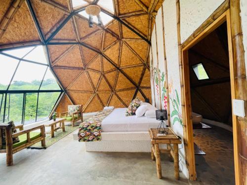 a bedroom with a bed in a large room with windows at Ecofuratena Glamping & Experience in Utica