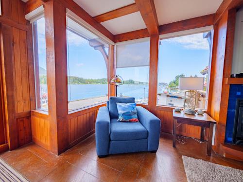a blue chair in a room with large windows at Whisky Harbour, Downtown King Bed and Inlet View in Ucluelet